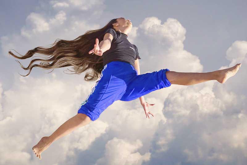 woman jumping through clouds with energy